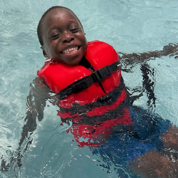Child swimming in a pool wearing a life jacket