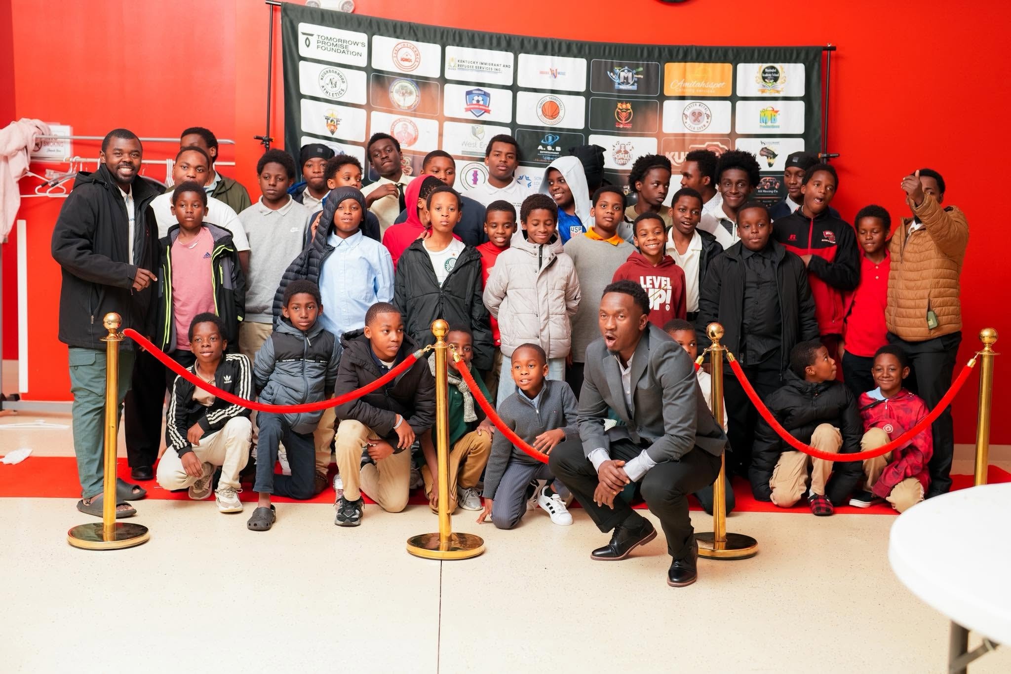 Youth gathered at a community event with a red backdrop