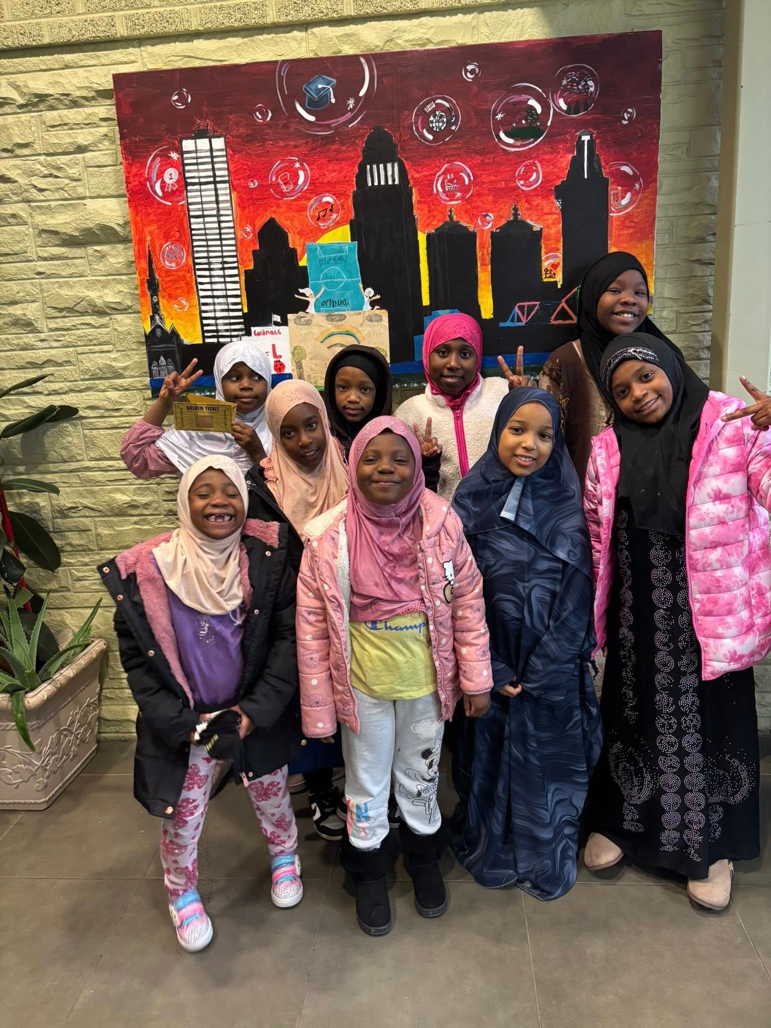 Young girls posing together near a city mural