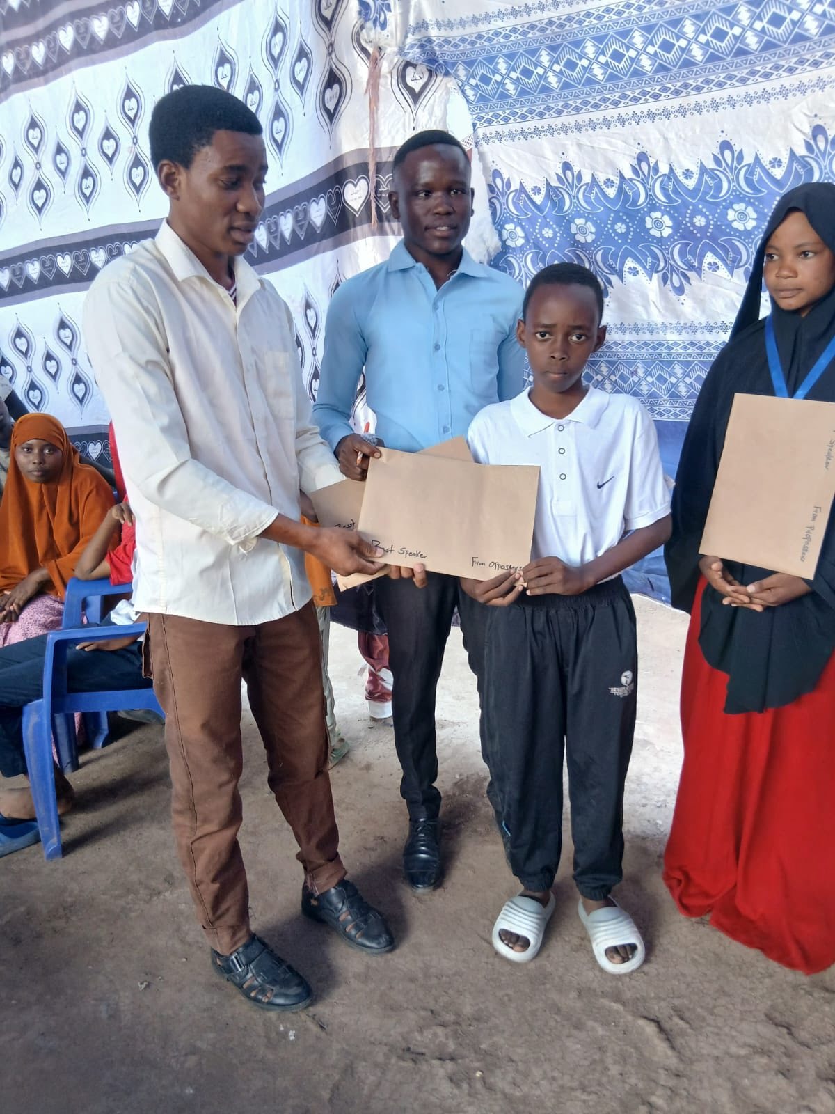 Adults presenting certificates to students indoors